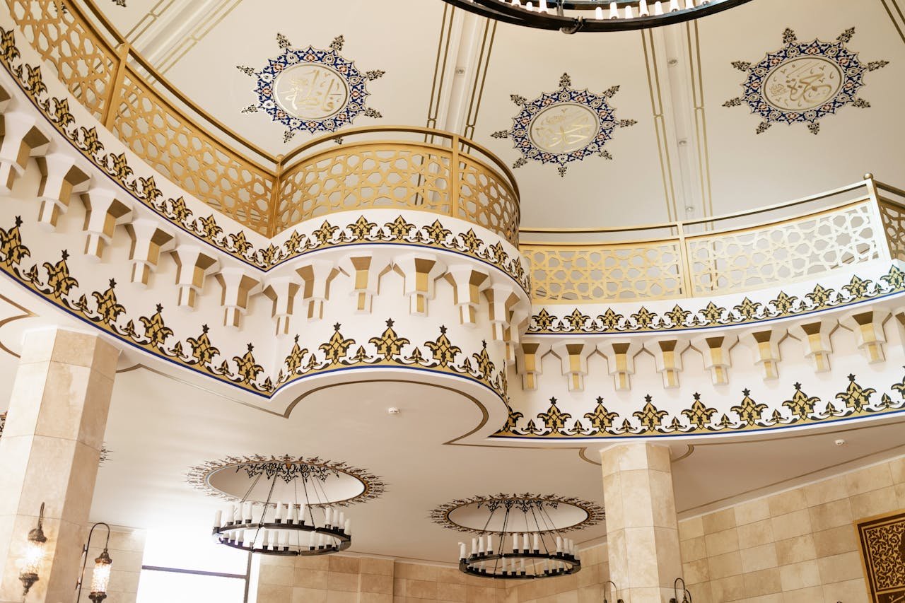 Elegant mosque interior showcasing intricate ceiling and ornate designs.